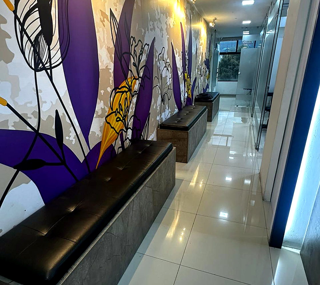 Pasillo interior del consultorio con mural y banca de espera