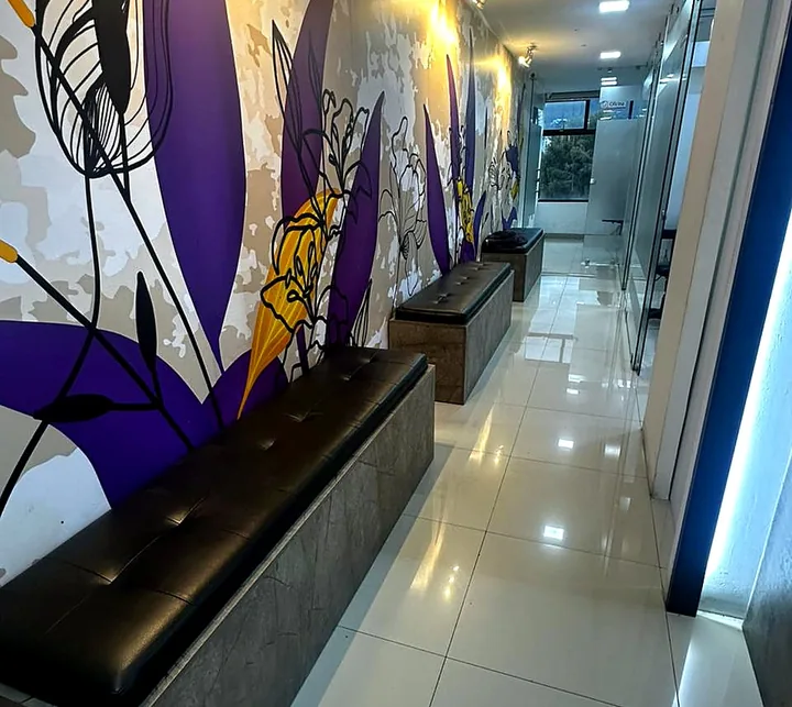 Pasillo interior del consultorio con mural y banca de espera